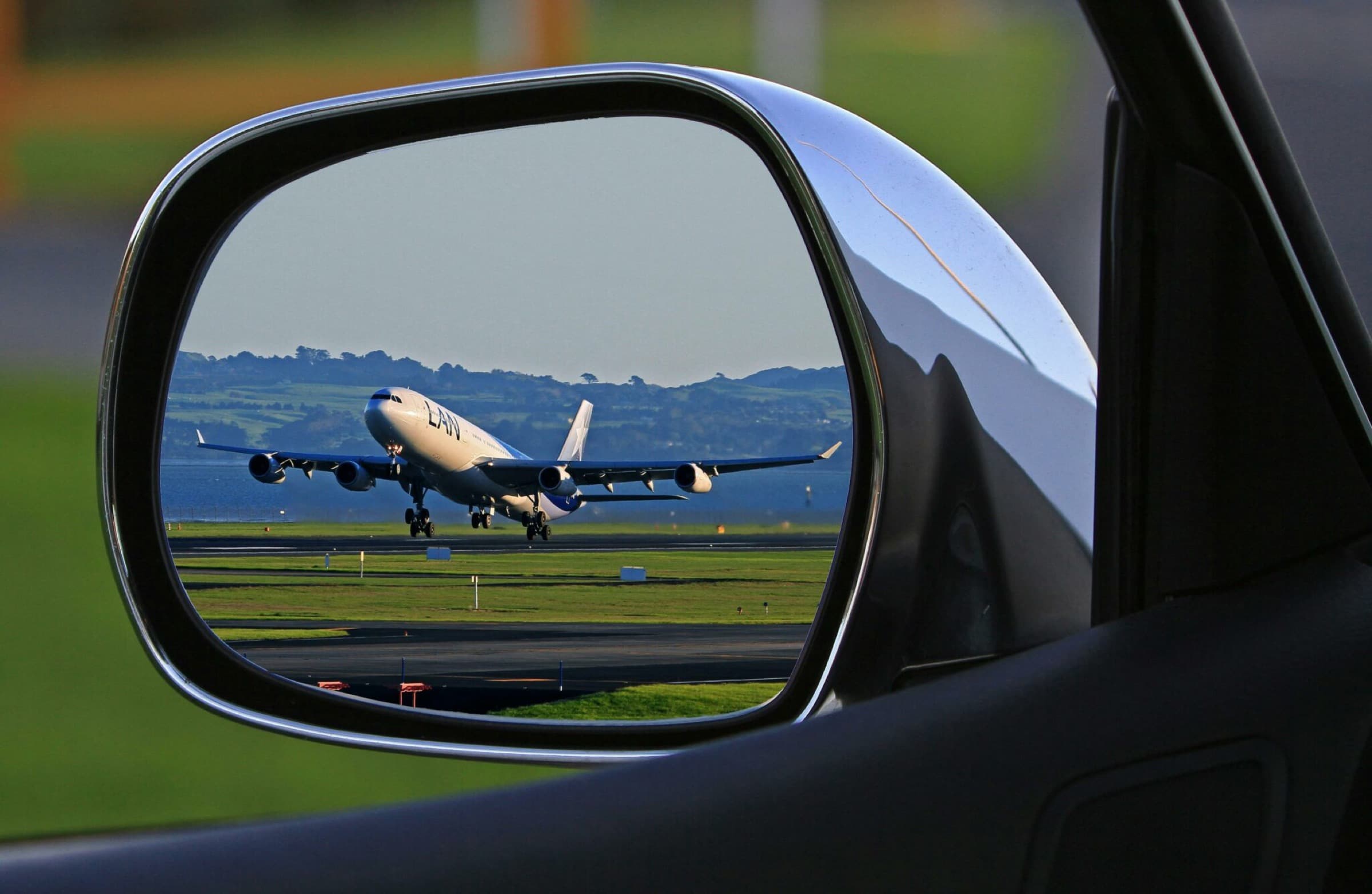 An aeroplane reflected in a car wing mirror